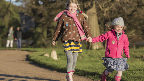 Two girls excitedly running down a path